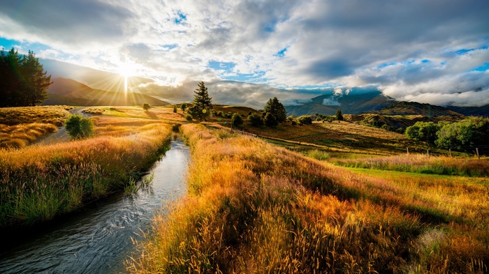 Sunset over a grassy field with a creek