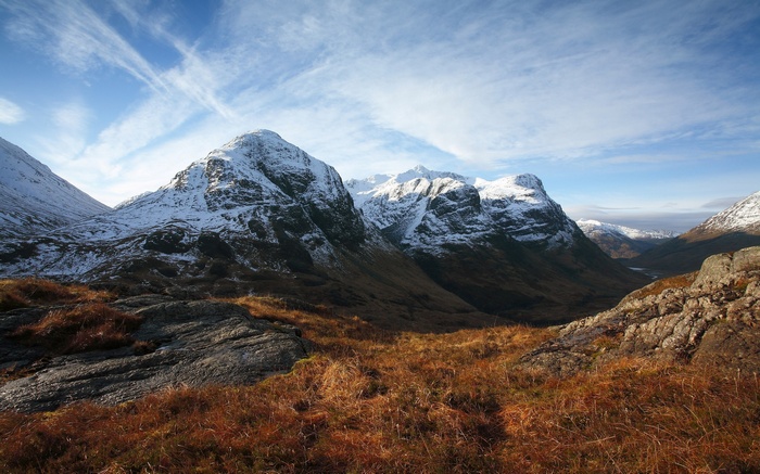 Snow-capped mountains in Glen Coe, Scotland under a cloudy sky