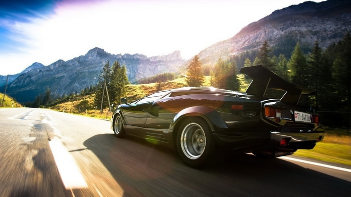 Black Lamborghini Countach driving on a mountain road