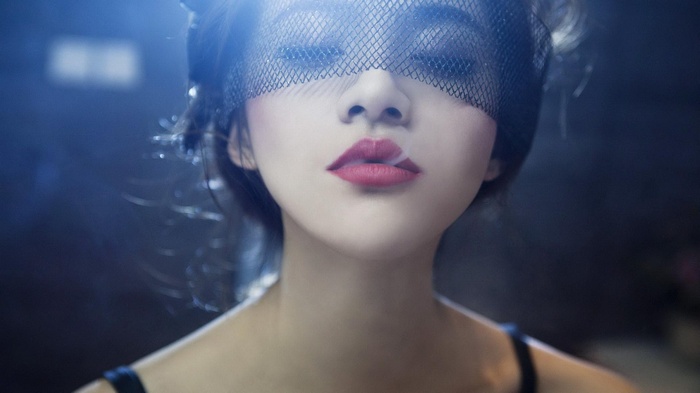 Woman wearing a black veil with smoke from lips