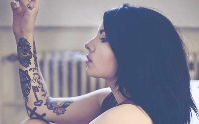 Woman with tattoos smoking, profile view