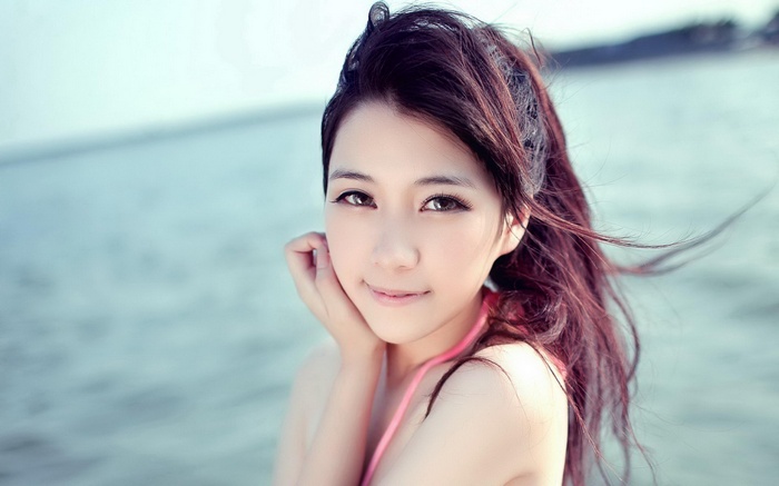 Asian woman looking at viewer at the beach