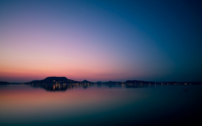 Twilight over a calm lake with distant hills