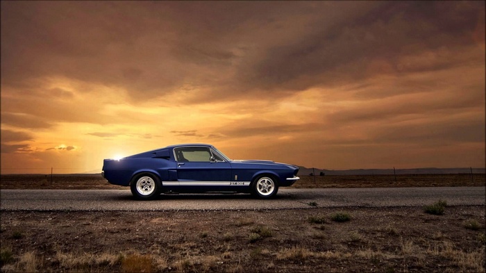 Blue Ford Mustang Shelby GT500 on a road at sunset