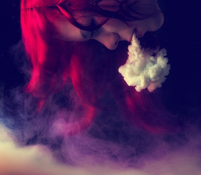 Woman with red hair exhaling smoke underwater