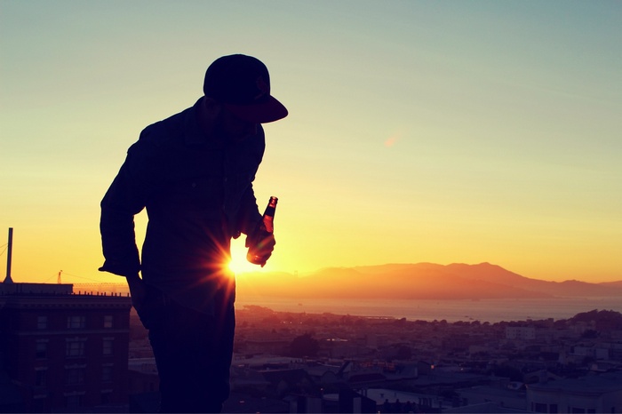 Man with beer on rooftop at sunset
