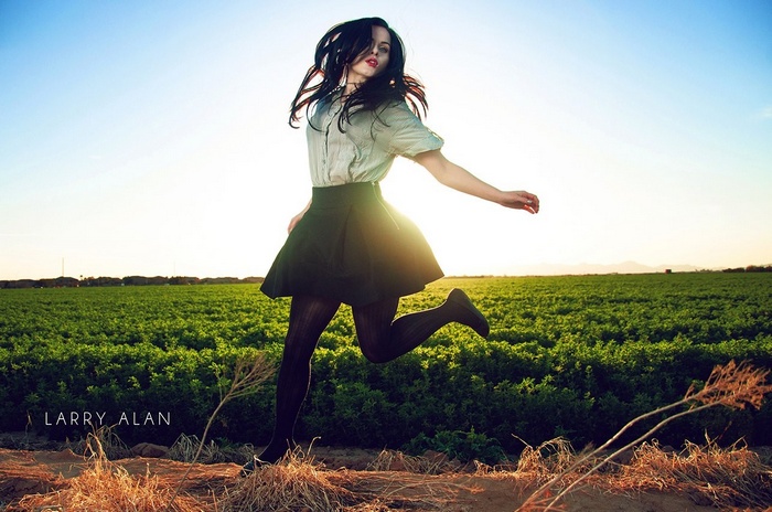 Woman jumping in a field with Larry Alan text