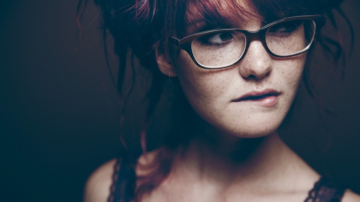 Woman with freckles and glasses biting her lip