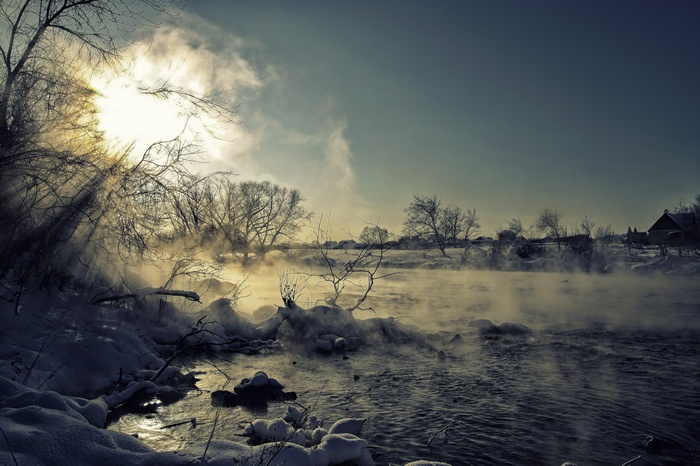 Winter landscape with sun and steam over a river
