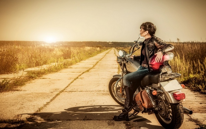 Woman in leather jacket on a motorcycle on a road