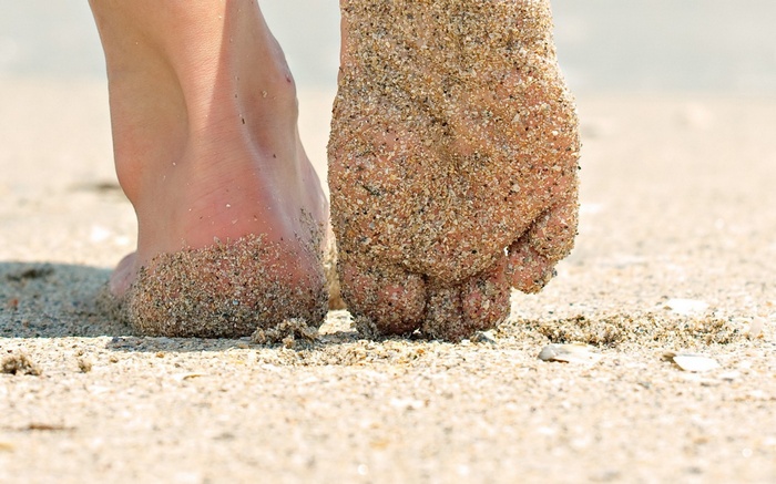 Feet covered in sand on a beach
