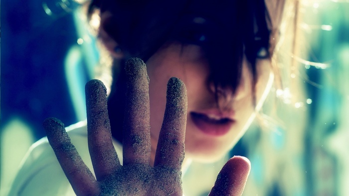 Woman with sand-covered hands looking at viewer