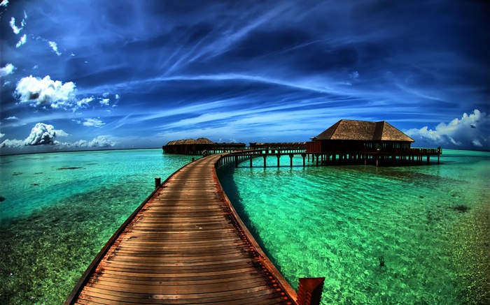 Wooden pier leading to overwater bungalows in turquoise water