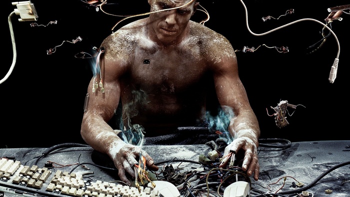 Shirtless man with wires and keyboards