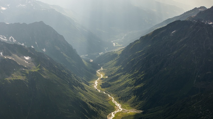 Sunlight streams through a mountain valley in Switzerland