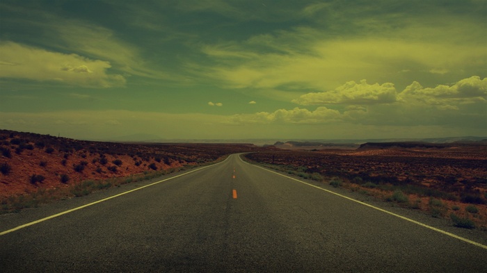 Desert road stretching into the distance under a cloudy sky