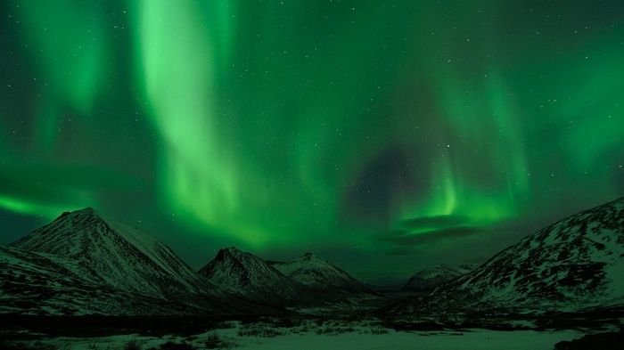Aurora borealis over snow-covered mountains at night