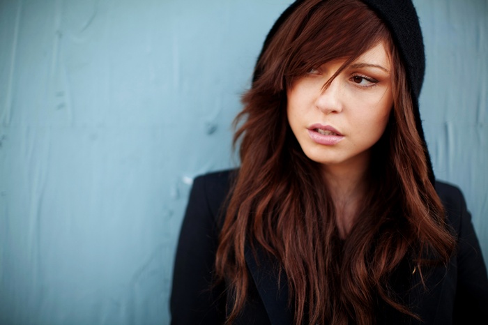Woman with long brown hair wearing a black hood