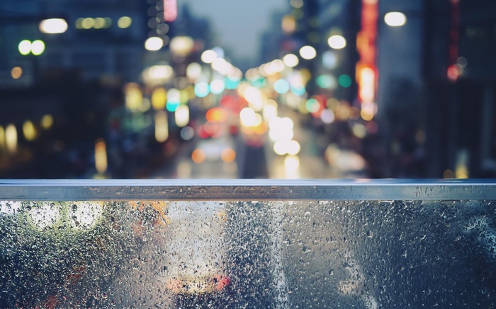 Rainy city street with bokeh lights and water drops on glass
