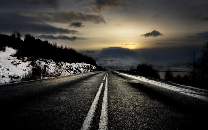 Winter road at sunset with snow and clouds