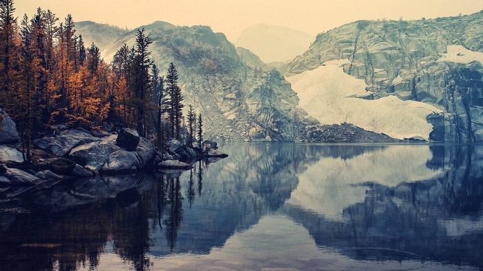 Lake reflection of autumn trees and snowy mountains