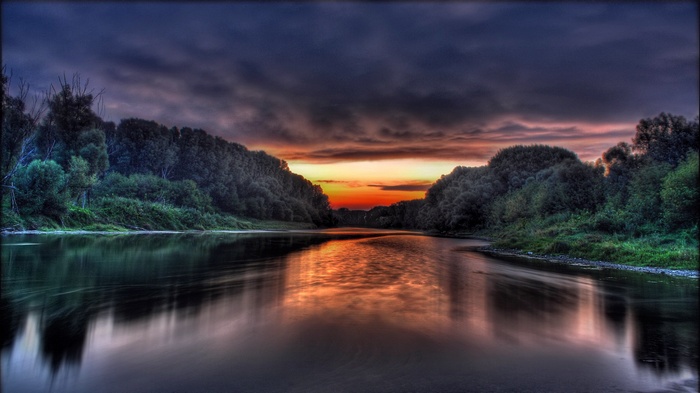 Sunset over a river with trees and clouds