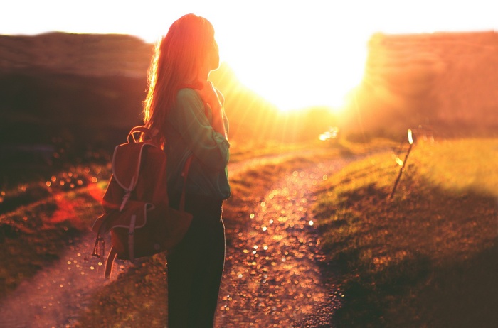 Woman with backpack in sunlight outdoors