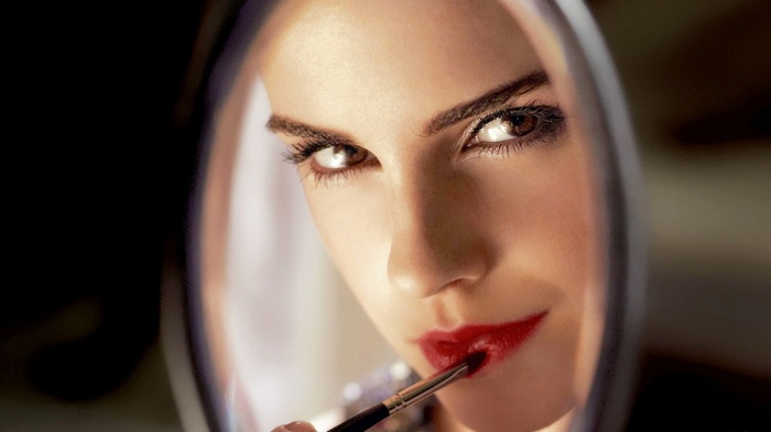 Emma Watson applying red lipstick in a mirror