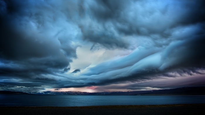 Stormy clouds over a calm sea and distant land