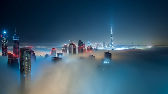 Dubai skyline shrouded in fog at night with Burj Khalifa