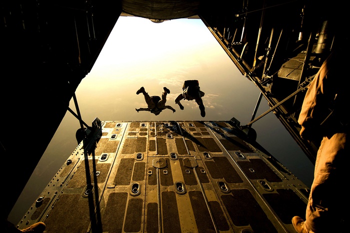 Military aircraft with skydivers jumping out