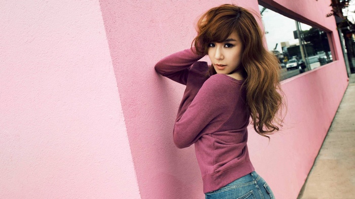 Tiffany from Girls Generation leans against a pink wall