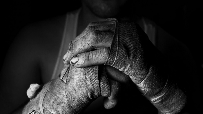 Monochrome close-up of boxer's hands wrapped in bandages