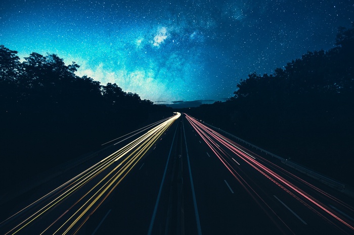 Highway at night with light trails under the Milky Way