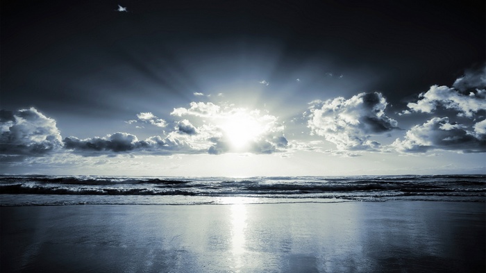 Sunlight breaking through clouds over a beach and sea