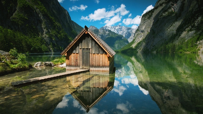 Wooden cabin on a lake with mountain reflection