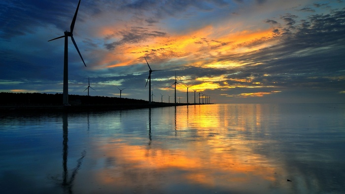 Wind turbines at sunset reflected in the water