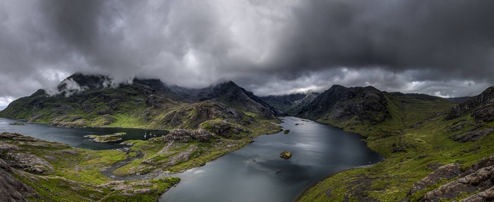 Panoramic view of a mountainous landscape with a lake under cloudy skies