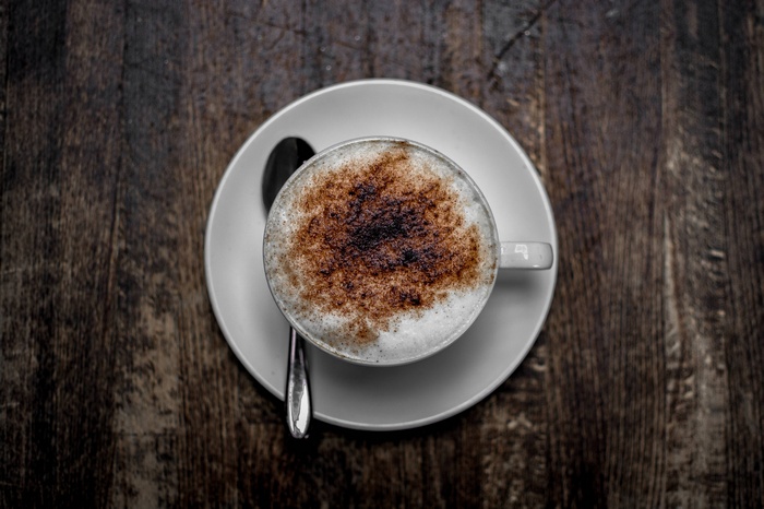 Cappuccino in a white cup on a saucer with a spoon