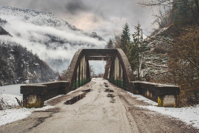 Concrete bridge over a misty mountain road in winter