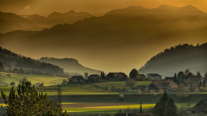 Misty mountains and village at sunset