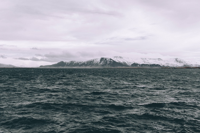 Ocean and snow-capped mountains under a cloudy sky