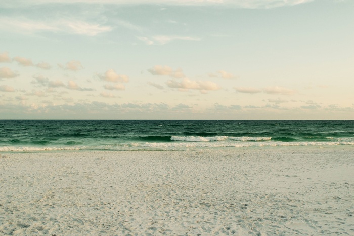 Ocean waves on a sandy beach under a cloudy sky