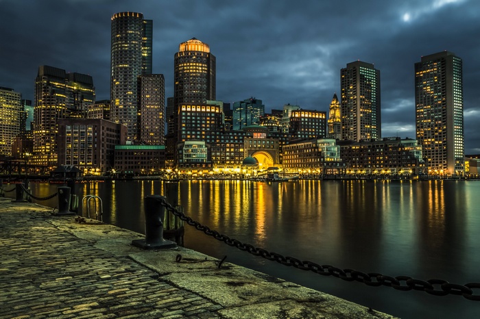 Boston cityscape at night with illuminated skyscrapers reflecting on water