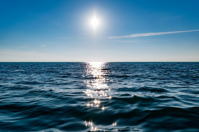 Sun reflecting on the ocean horizon under a clear blue sky