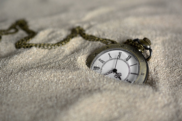 Pocket watch buried in sand