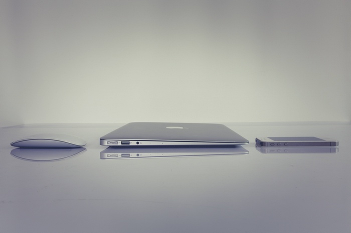 Apple MacBook, iPhone, and Mouse on a Reflective Surface