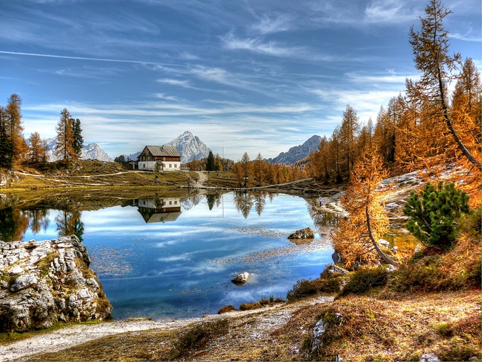Alpine lake with house and mountains in Dolomites, Italy