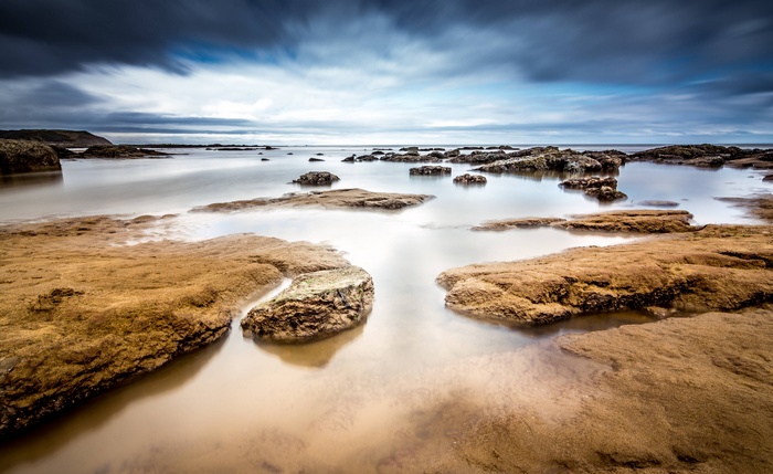 Rocky beach with calm water and dramatic clouds