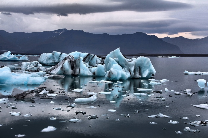 Icebergs floating in a glacial lagoon with mountains in the background